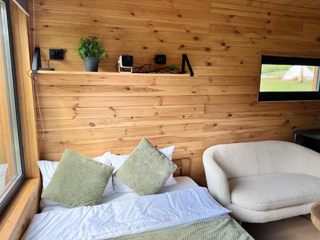 ein Schlafzimmer mit einem Bett und einem Stuhl und einem Fernseher in der Unterkunft глемпінг Обійми in Yatski
