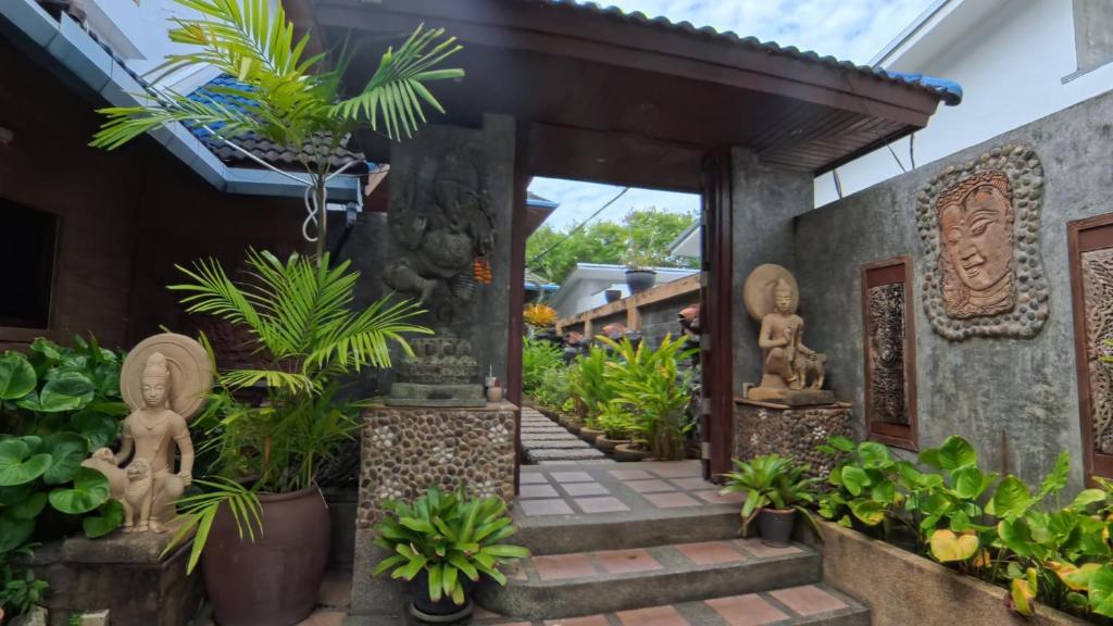 an entrance to a house with plants and statues at The Nai Harn Collective in Rawai Beach