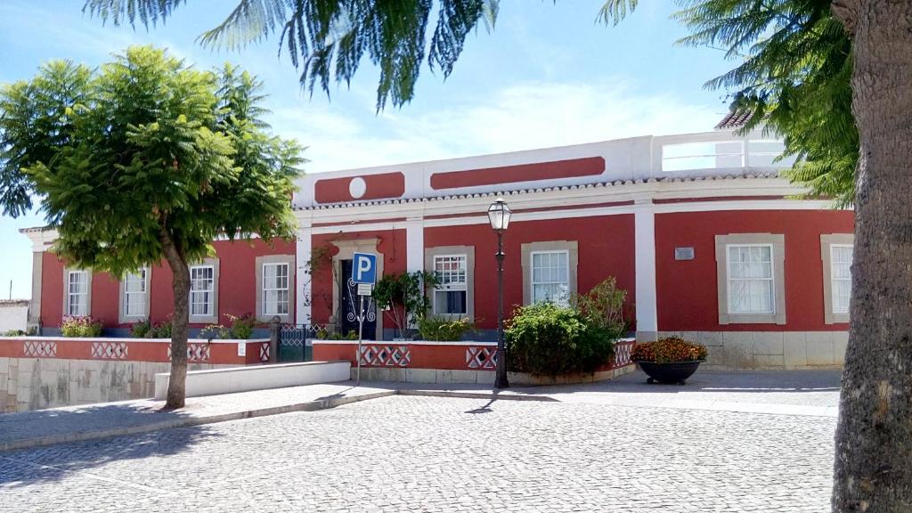 un edificio rojo y blanco con un árbol delante de él en Casa18.55 - Time with history, en São Brás de Alportel
