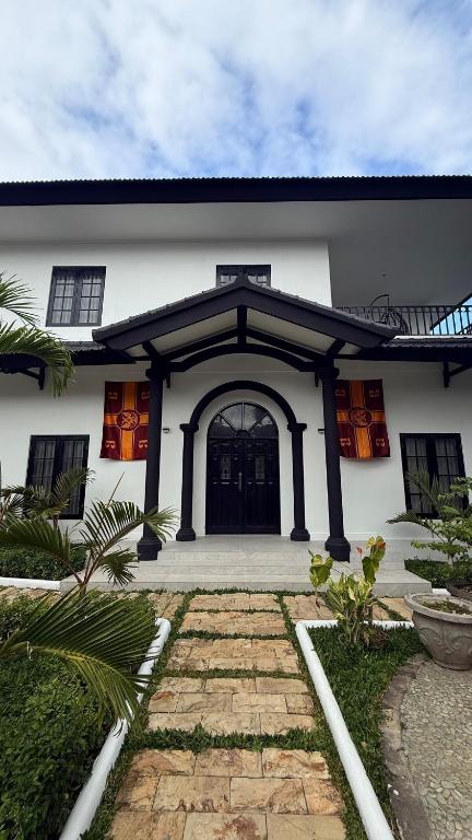 a white house with a black door and a courtyard at White Swan Mansion in Ketewel