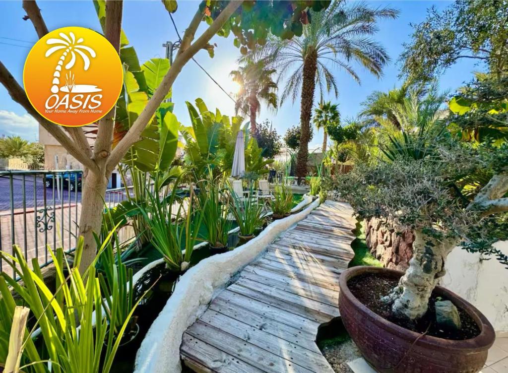 un giardino con alberi e piante su un sentiero di legno di OASIS GARDEN a Eilat