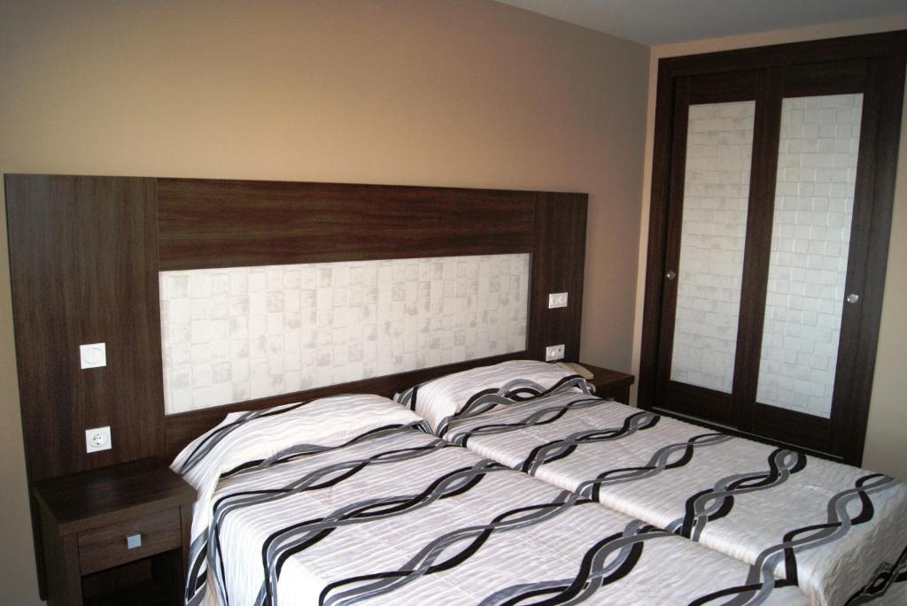 a bed with a wooden headboard in a bedroom at Hotel Doña Luisa in San Luis de Sabinillas