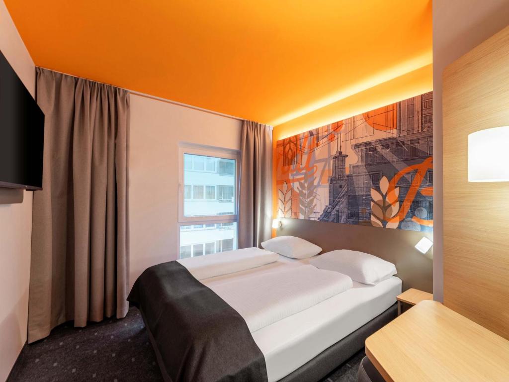 Un dormitorio con una cama grande y una ventana. en B&amp;B HOTEL Hagen, en Hagen