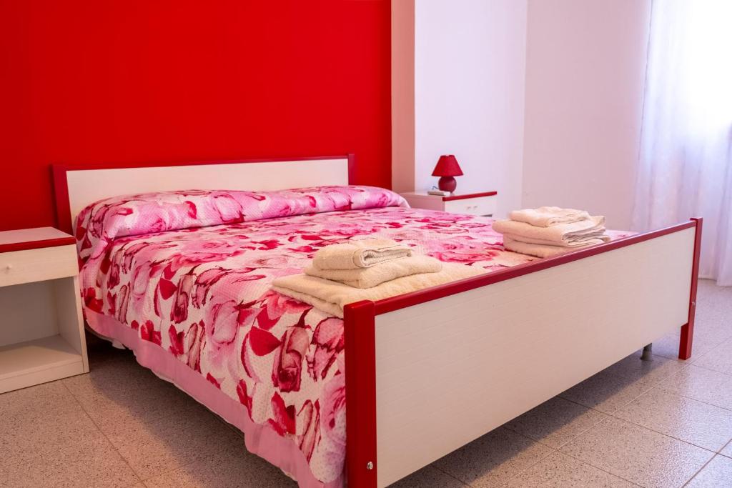 ein rotes Schlafzimmer mit einem Bett mit Handtüchern darauf in der Unterkunft Sun House in Santa Maria del Cedro