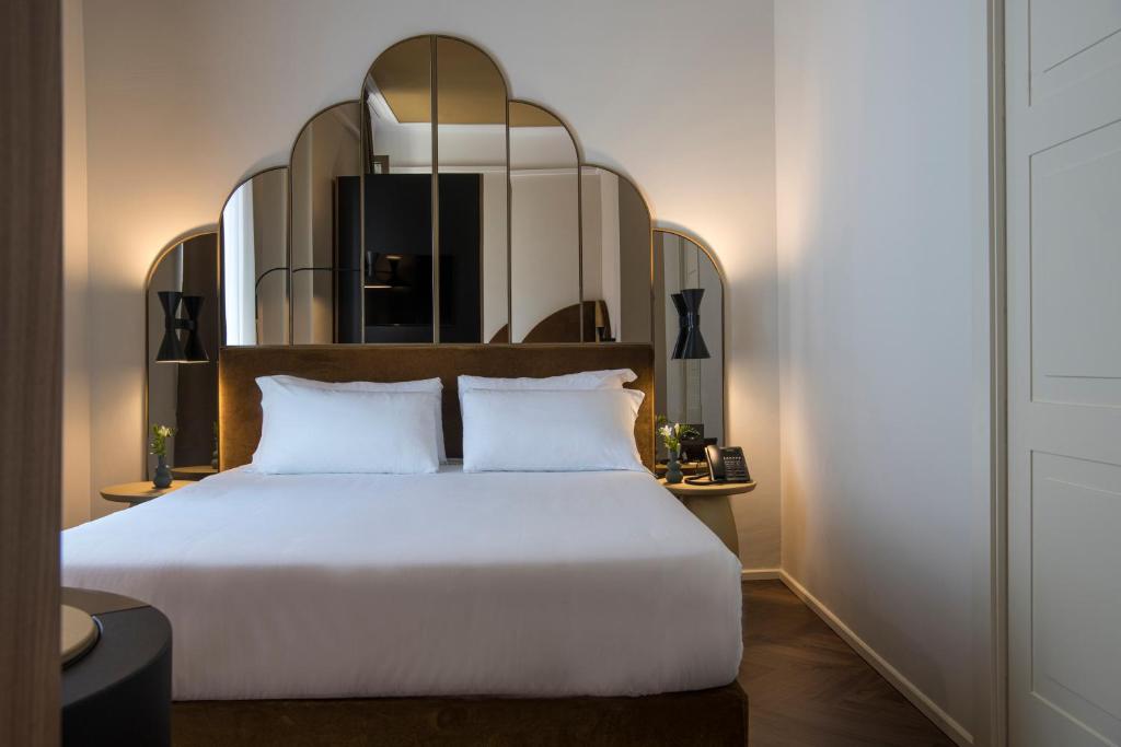 a bedroom with a white bed and a mirror at Palazzo Buenos Aires in Milan