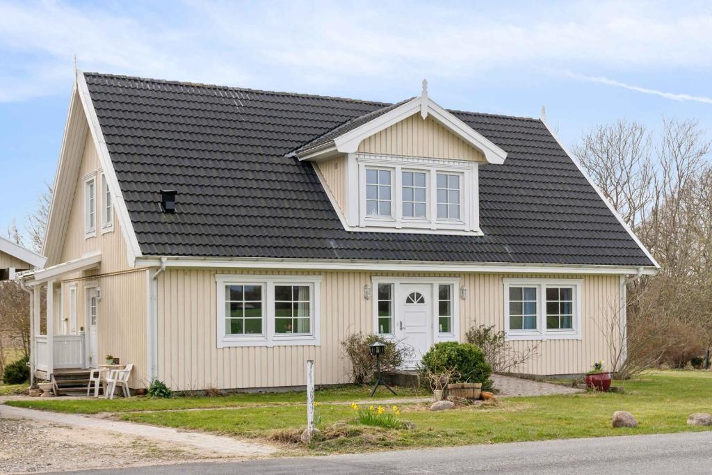 a white house with a black roof at Spacious Villa In The Countryside Near The Beach in Fakse Ladeplads