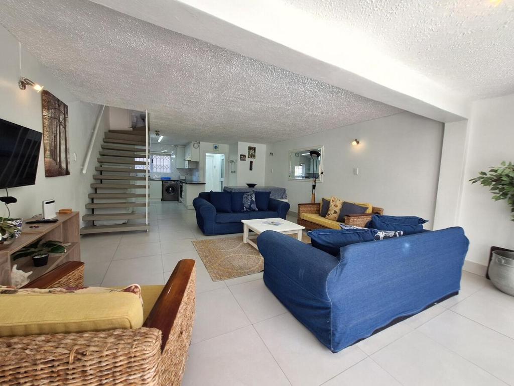 a living room with blue couches and a staircase at Holiday home by the River with Jetty in Port Alfred