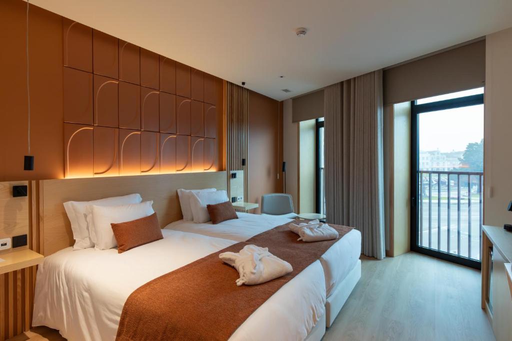 Una habitación de hotel con dos camas y balcón. en Hotel do Alboi, en Aveiro