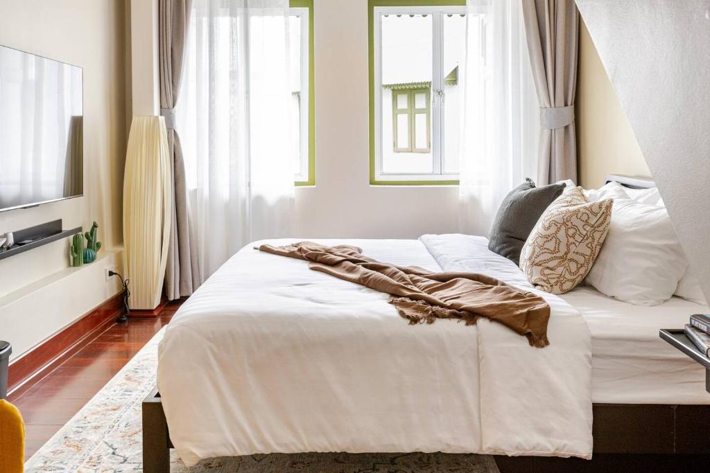 a bedroom with a bed with white sheets and pillows at Nueng Rana 232 Corner view 1BR Duplex 3beds / 2B in Samphanthawong
