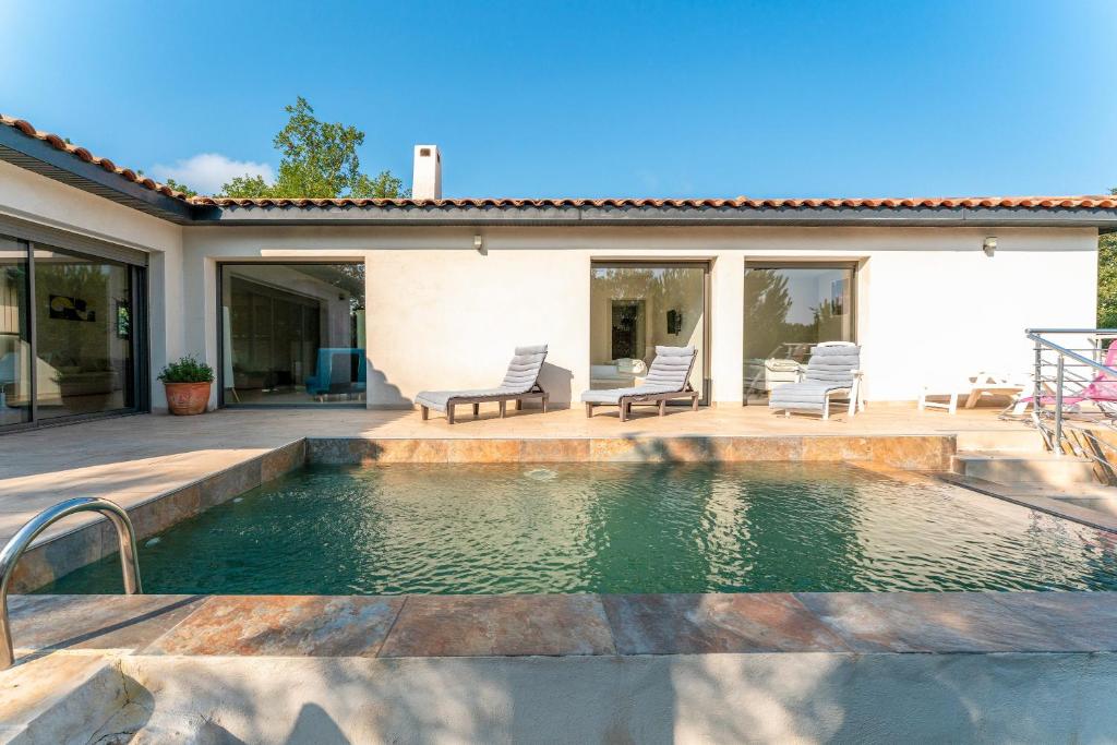 une piscine avec des chaises et une maison dans l'établissement Villa Au Bord Du Gardon, à Russan