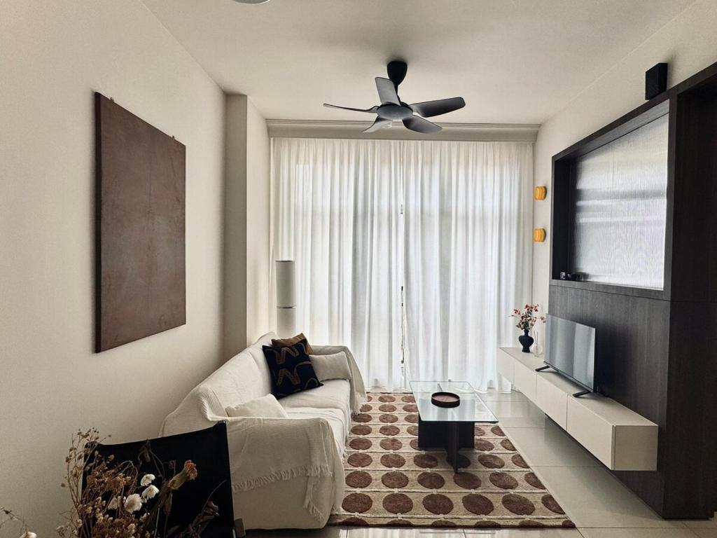 a living room with a white couch and a ceiling fan at Cosy Comfort Suite 3BR at Midas Seri Alam in Masai