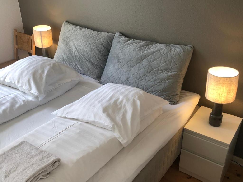 a white bed with two pillows and two lamps at Huset ved springvandet in Randers