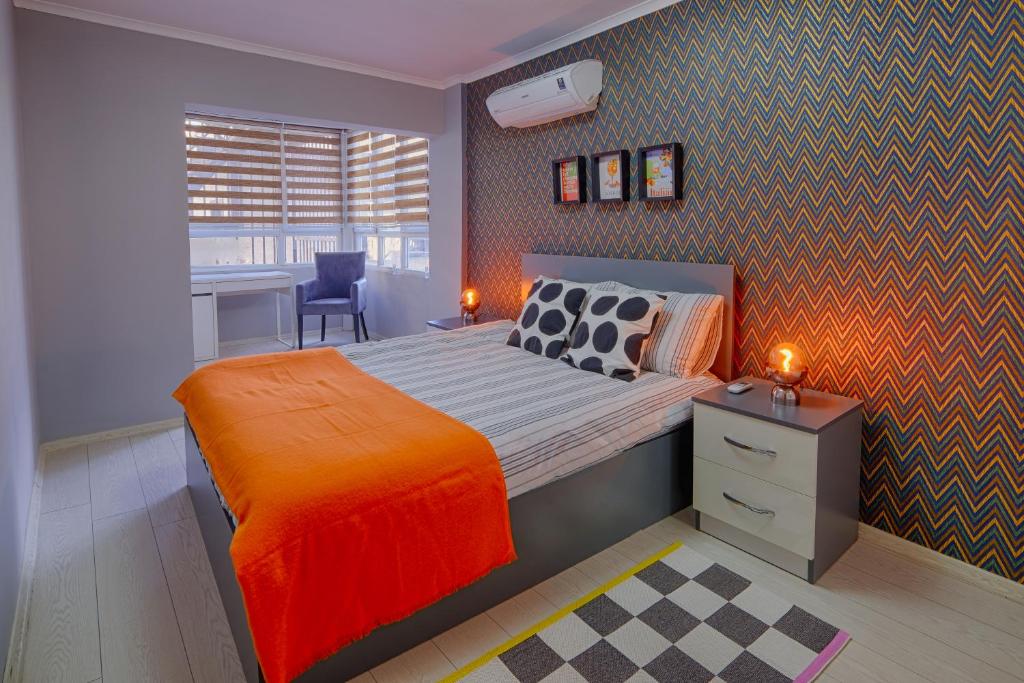 ein Schlafzimmer mit einem großen Bett und einer orangefarbenen Decke in der Unterkunft Maxihomes Near Hadrian Gate & Beach, with Sea Views in Antalya
