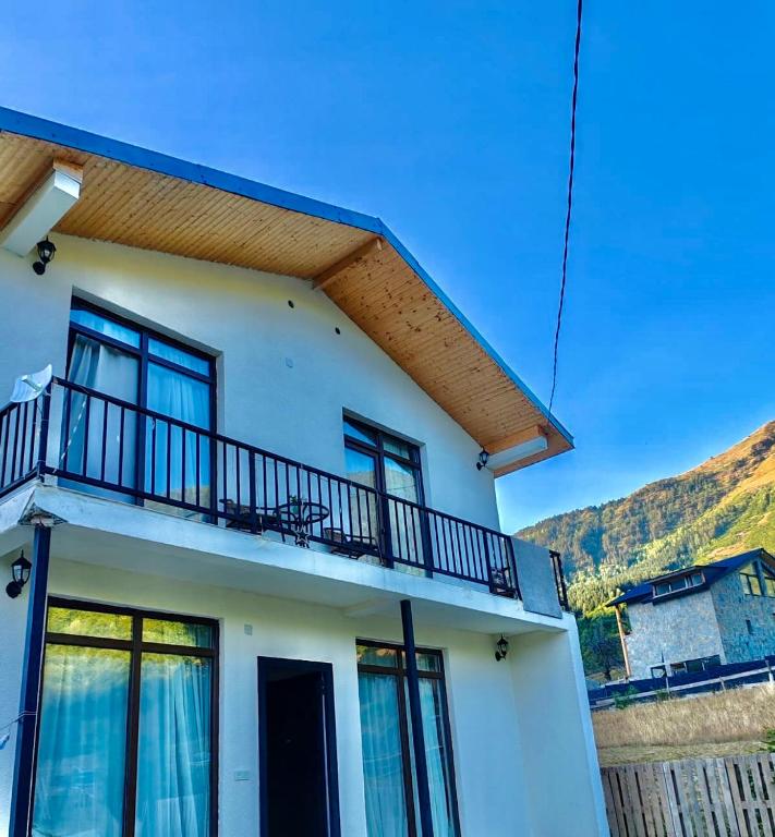 a white house with a balcony on top of it at Hillside Mestia ჰილსაიდ მესტია in Mestia