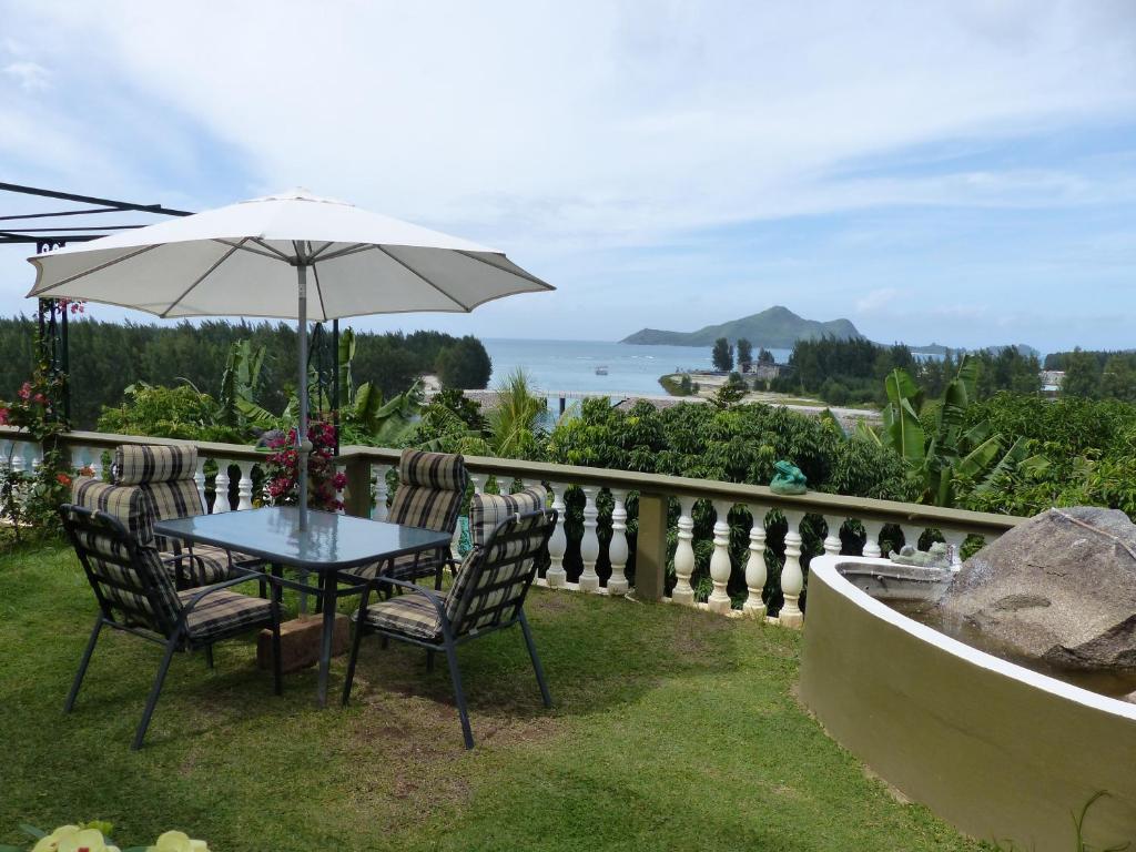 a table and chairs with an umbrella and the ocean at Hibiscus House Seychelles Self Catering in Victoria