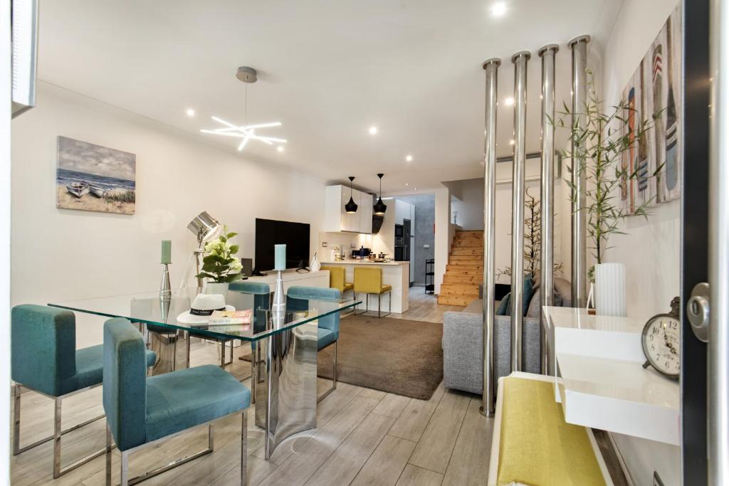 a dining room and living room with a glass table and blue chairs at Casa dos Quatro in Faro