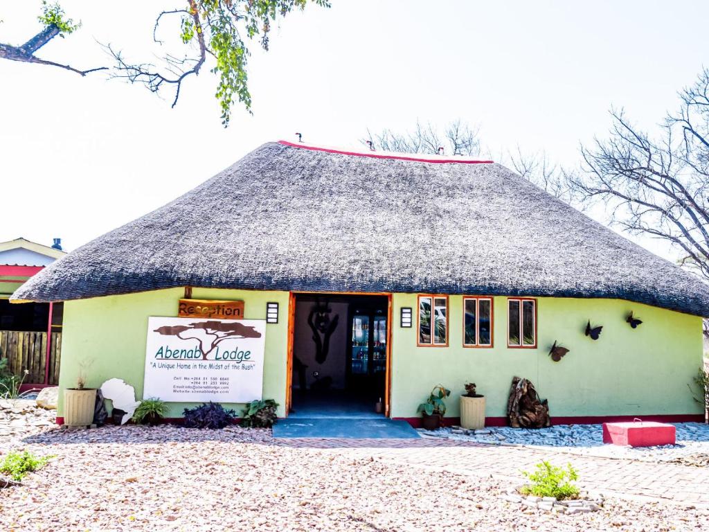 una casa con il tetto di paglia e un cartello sulla porta di Abenab Lodge & Tours cc a Grootfontein