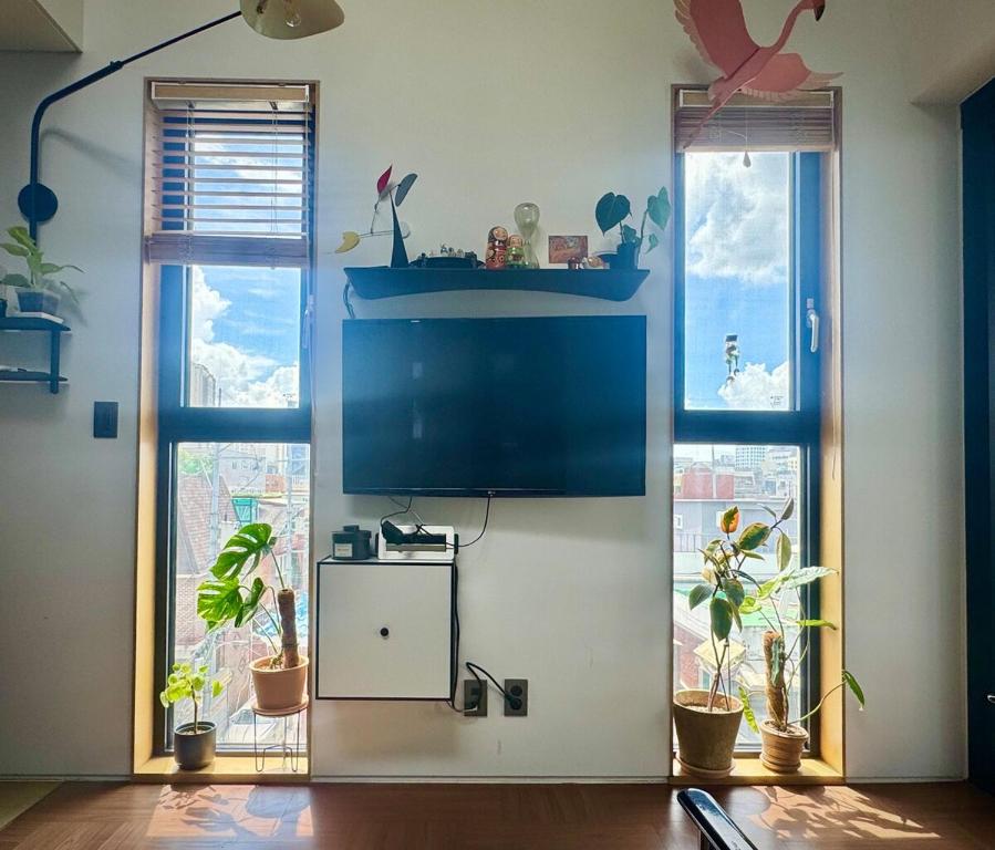 a living room with a tv and two windows at Rooftop House Seongsu in Seoul