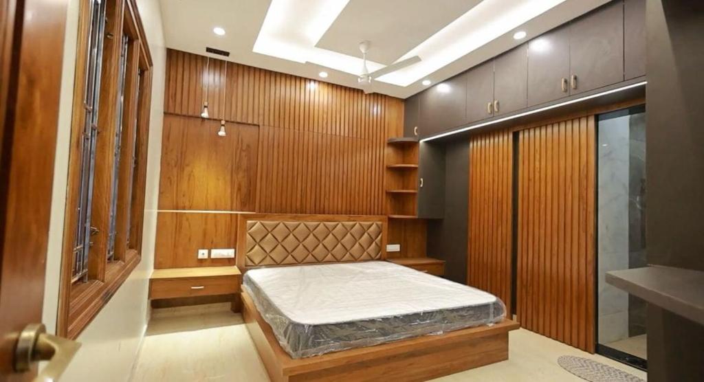 a bedroom with a bed in a room with wooden walls at Samsthaanam - Luxury 3BHK Villa with Pool in Udupi in Kalyānpur