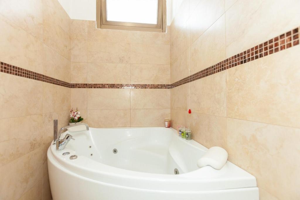 Una bañera blanca en un baño con ventana. en Bright Villa with Balcony and Jacuzzi, Milan Area, en Cesate