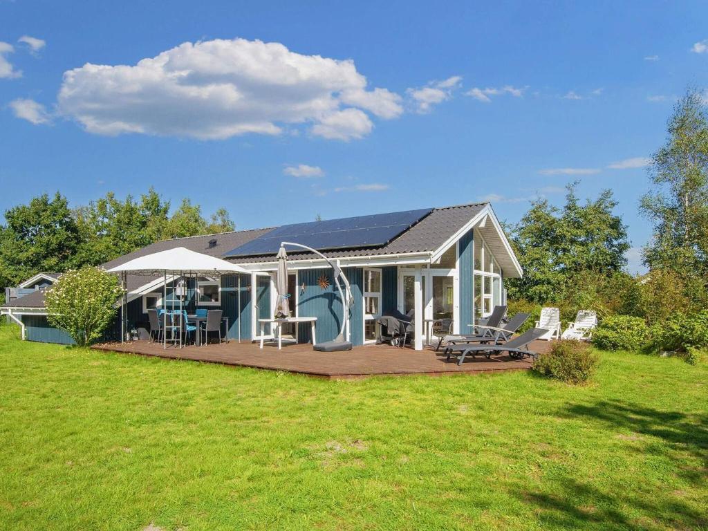 a house with a deck and chairs on a field at Luxury Retreat near Beach - By Traum Ferienwohnungen in Sønderby