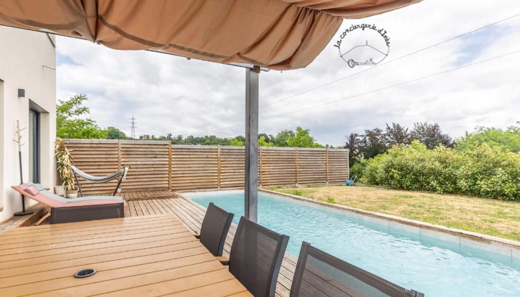 eine Terrasse mit Stühlen und einem Sonnenschirm neben einem Pool in der Unterkunft La Beaumière #Piscine#Garage in Ceyrat