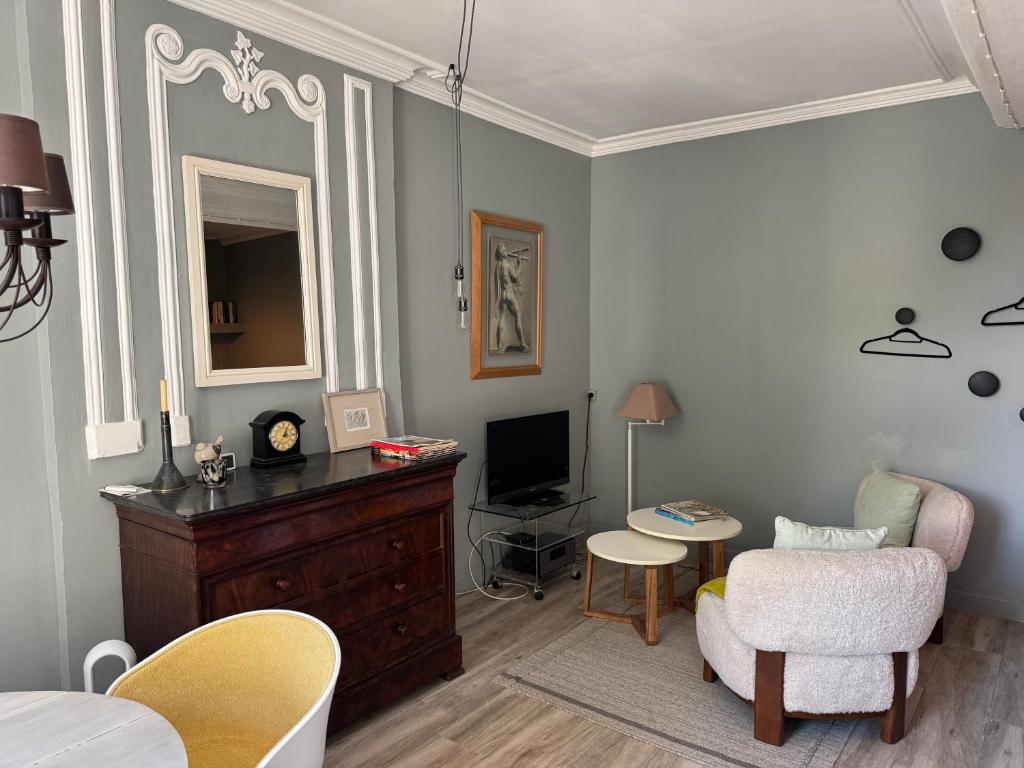 a living room with a table and a chair and a television at Le studio du Clos du Bourgage in Saint-Pierre-dʼAutils