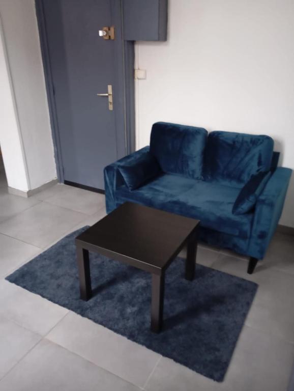 un sofá azul y una mesa de centro en la sala de estar. en T2 rénové proche métro, en Lille