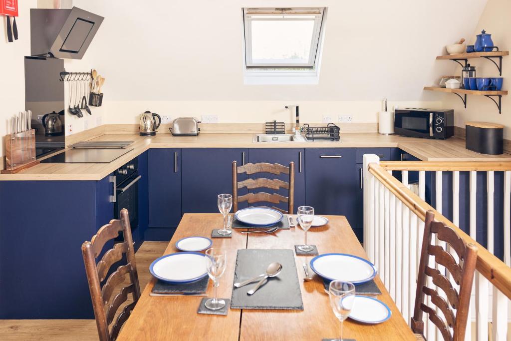 una cucina con tavolo in legno e piatti di Relaxing Countryside Retreat with Garden & Parking 