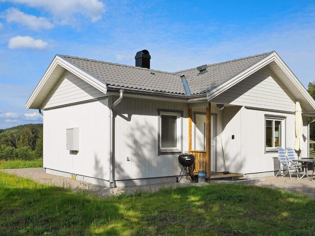 a small white house with a patio in a field at 4 star holiday home in Ljungskile in Ljungskile