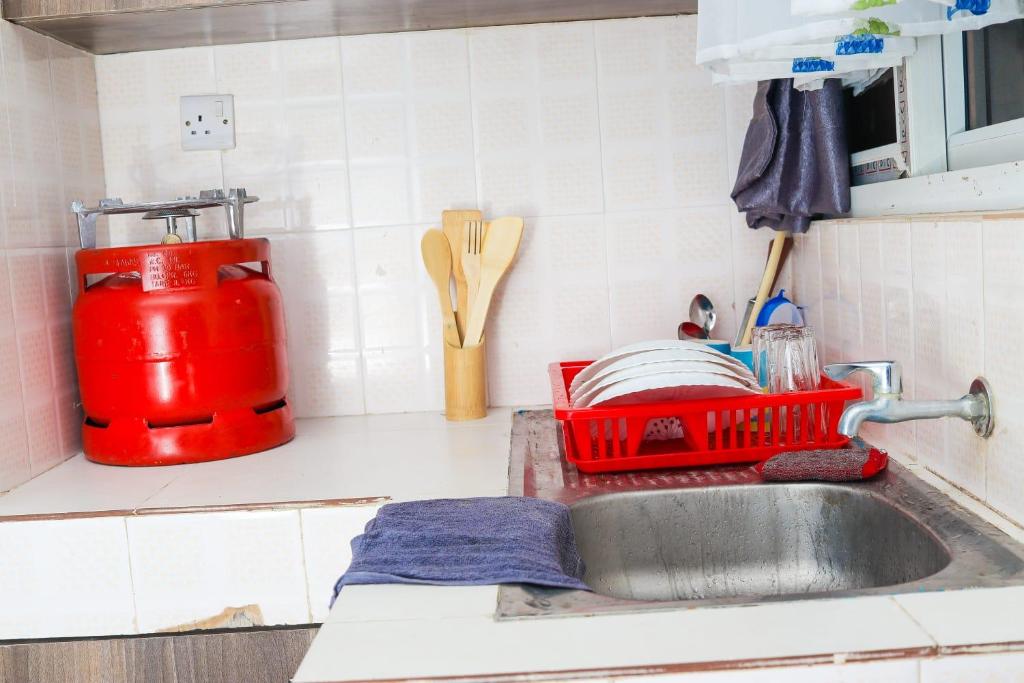 a kitchen sink with a red dish drying rack next to it at Dee's Super Luxury Studio Apartment Bamburi in Mombasa