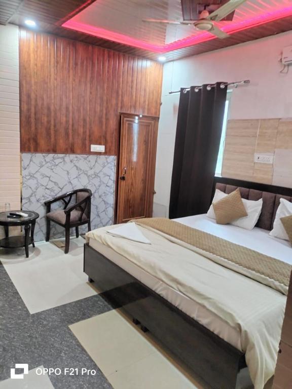 a bedroom with a large bed and a chair at HOTEL SATYA in Dehradun