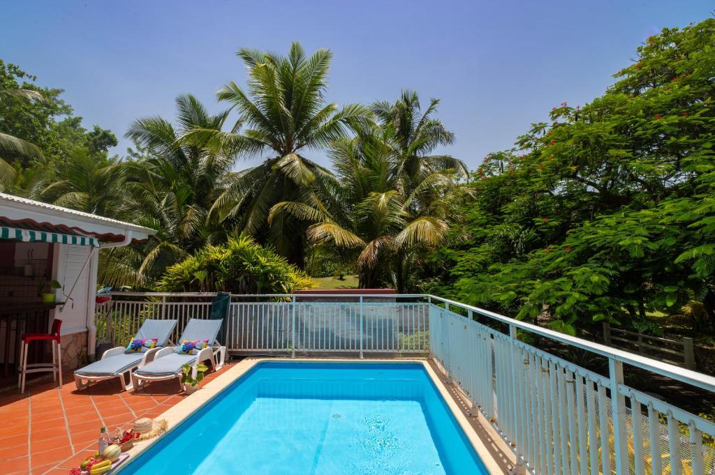 una piscina con 2 tumbonas y árboles en Villa Hibiscus, en Le François