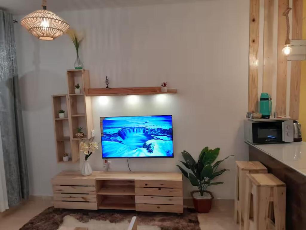 BungomaにあるBgm comfy lovely studio h4の壁に薄型テレビが取り付けられたリビングルーム