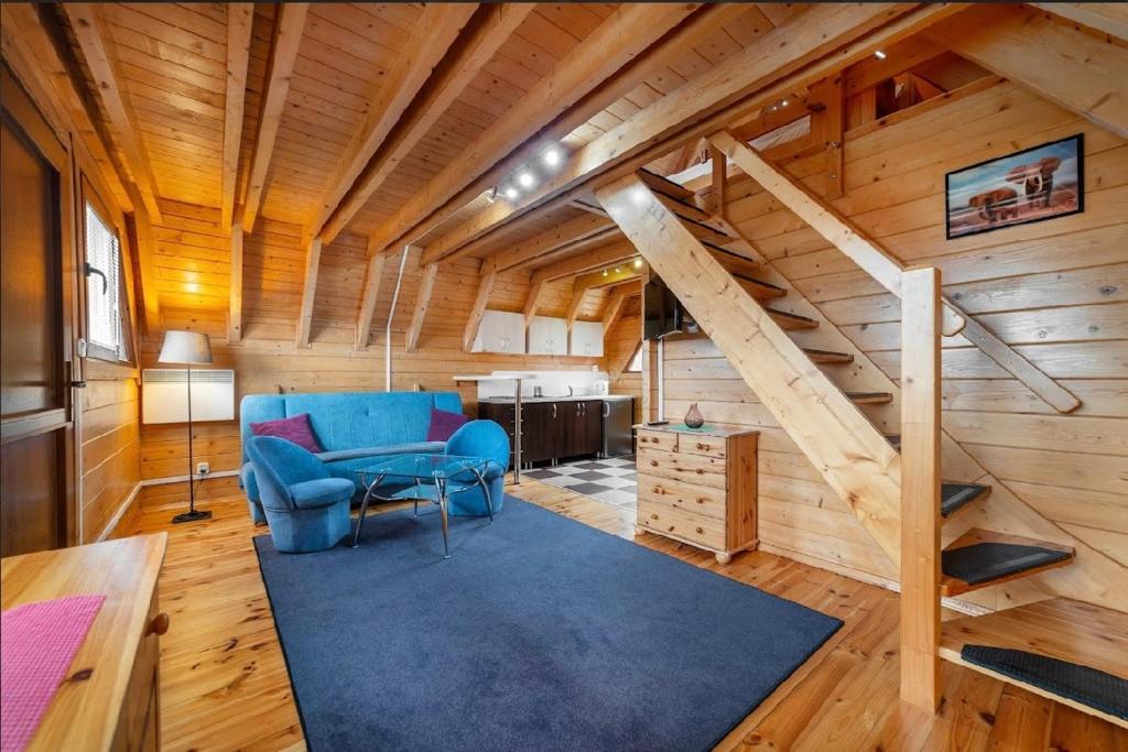 a living room with a blue chair and a staircase at Domki Port Jastarnia in Jastarnia