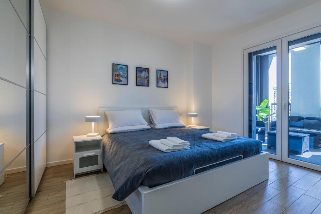 a bedroom with a king sized bed with blue sheets at Prime Living Milano Merlata - Balcony Apartment in Milan