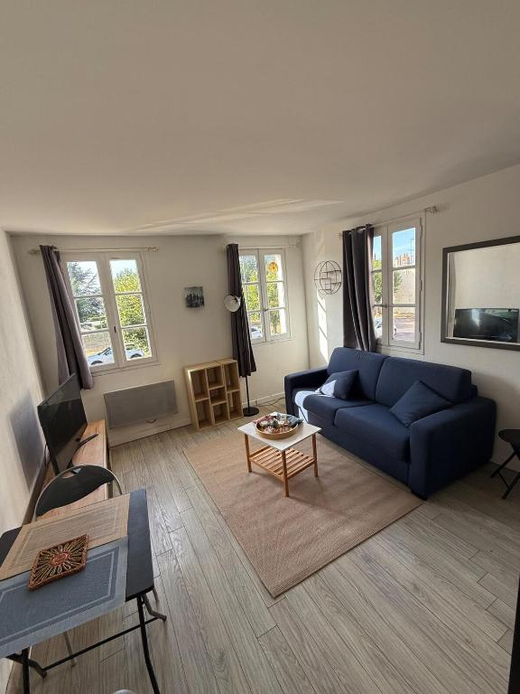 a living room with a blue couch and a table at Studio au cœur du village d'arts in Dives-sur-Mer