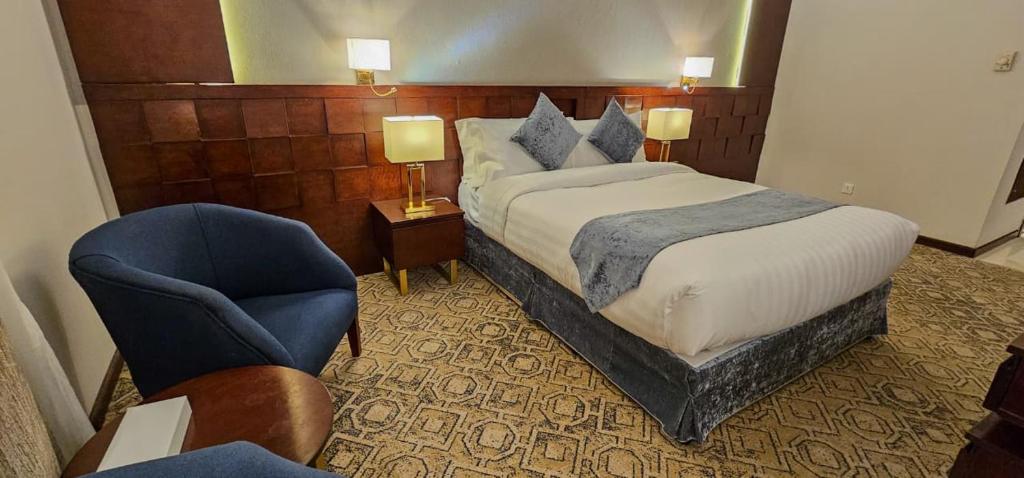 a hotel room with a bed and a chair at Jiwar Al Saha Hotel in Al Madinah