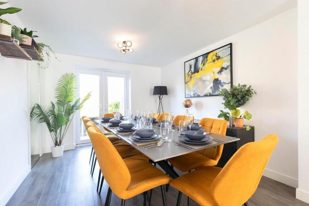 a dining room with a long table and yellow chairs at Stunning 4 Bed 3 Bathroom Home in Gloucestershire