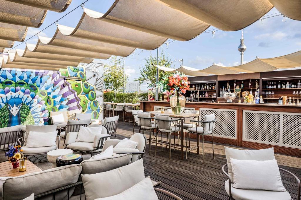 a rooftop patio with tables and chairs and a bar at Hotel AMANO Rooms & Apartments in Berlin