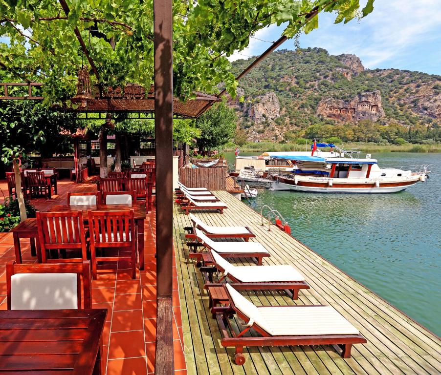 una fila de mesas y sillas en un muelle con un barco en Midas Pension, en Dalyan