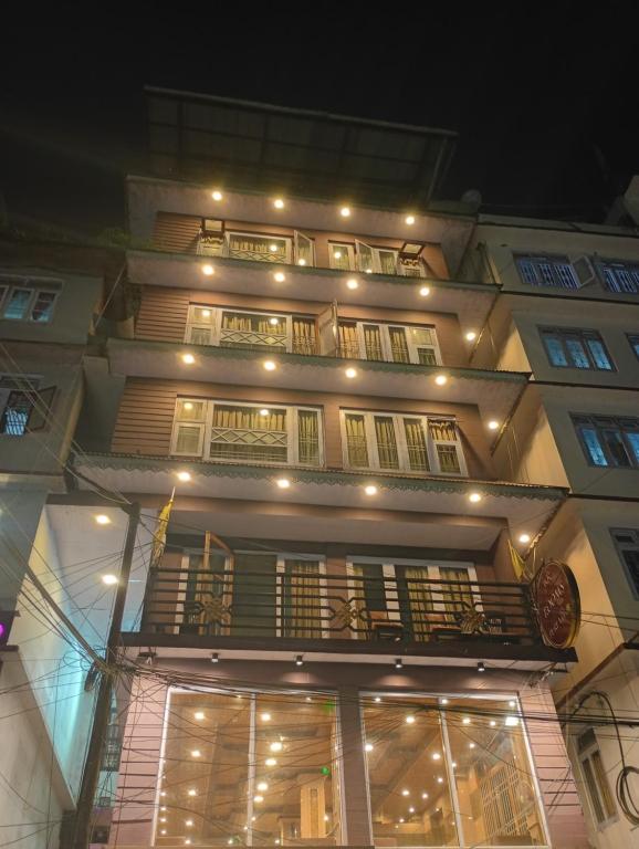 un grand bâtiment avec un balcon éclairé dans l'établissement Hotel Mayalne, à Gangtok