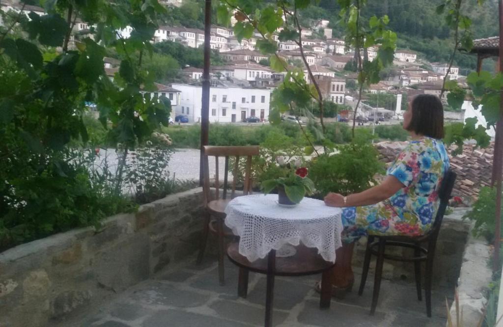 una mujer sentada en una mesa frente a una ventana en Hostel Mangalem, en Berat