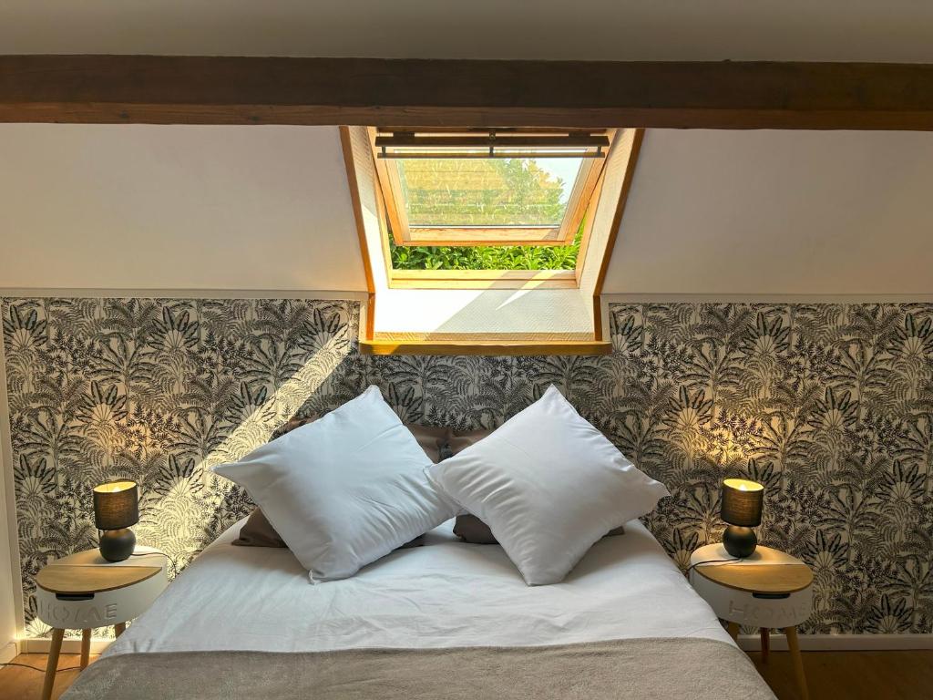 a bedroom with a bed with two pillows and a window at Maison Lilou in Garnay