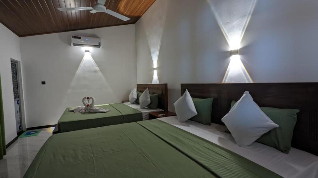 a bedroom with two beds with green and white pillows at MPS Paradise villa in Tangalle