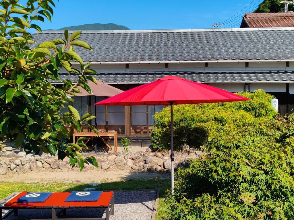 a red umbrella and a table and a bench at 釜炒り茶の宿陽だまりTraditional Japanese house near Kumano Kodo and Nachi Falls with parking bikes garden and onsite tea house in Nachikatsuura