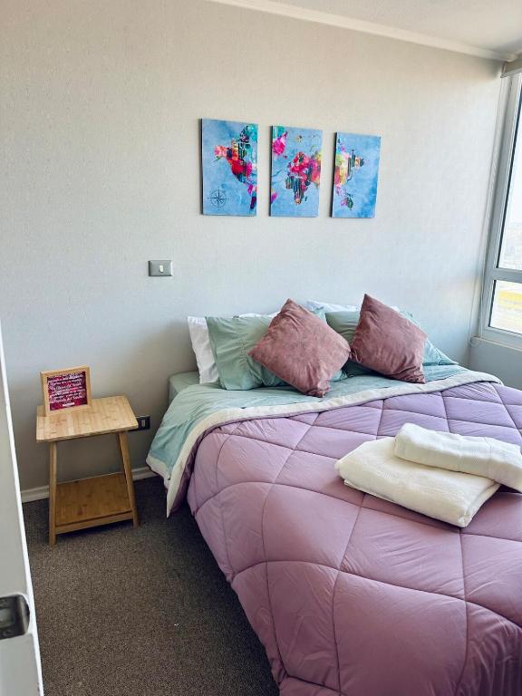 a bedroom with a purple bed with paintings on the wall at Central apartment CCP in Concepción
