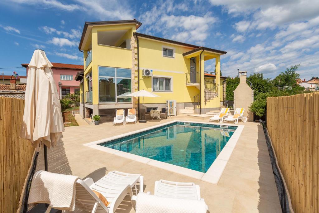 une villa avec piscine devant une maison dans l'établissement Villa Sandra, à Kaštelir