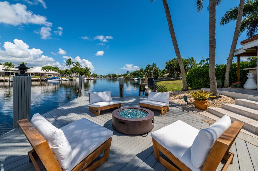 a patio with chairs and a fire pit next to the water at Luxury Channel Villa, Boat Dock and Private Pool, 5BR in Fort Lauderdale