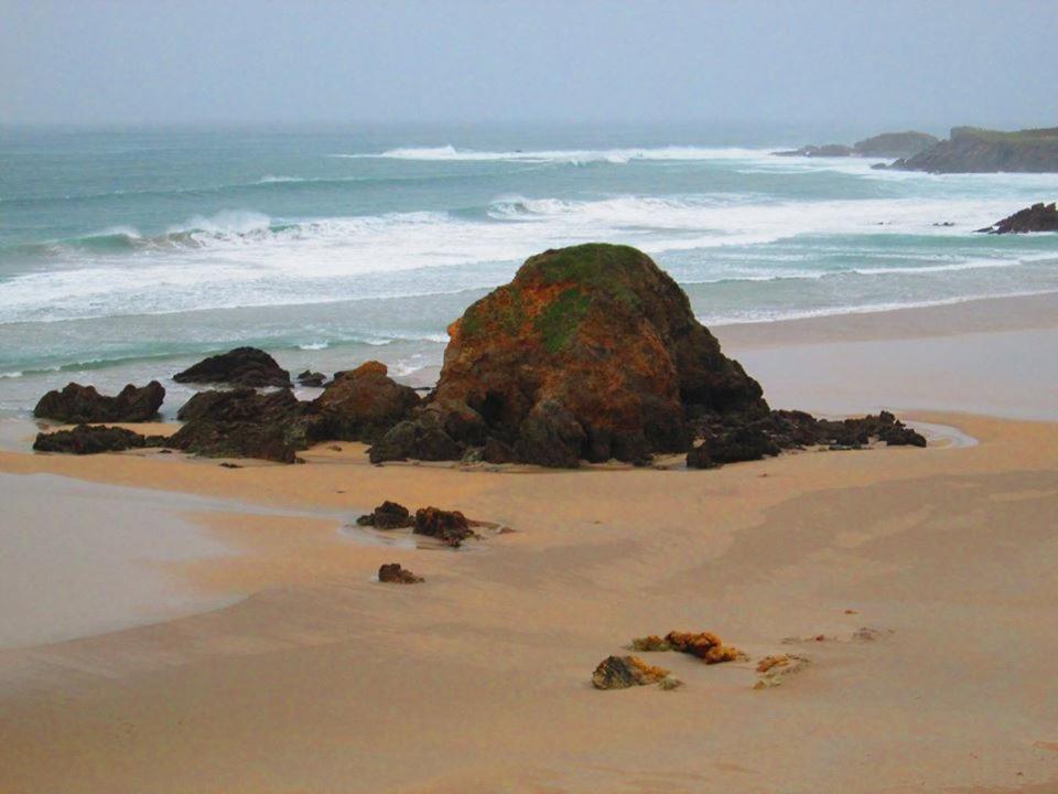 una gran roca en una playa con el océano en Hostal Restaurante Parajes en Castropol